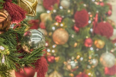 Ön planda sarı süsleme toplarıyla Noel ağacı süsleme ışıklarının bulanık arkaplanı.