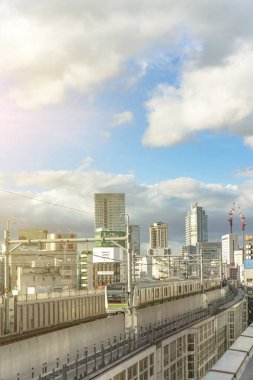 Tokyo, Japonya - Eylül 08 2019: Kanda İstasyonu Yamanote hattının trenlerinin Chiyoda 'nın binalarının arasından geçtiği yer Tokyo' nun mavi gökyüzünün altında.