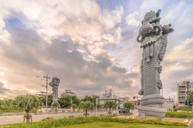 Naha, Japonya - 15 Eylül 2018: Çin'deki kardeş şehirler Naha ve Fuzhou'nun sembolü olan Naha Port Cruise Terminali rıhtımına yakın bir yerde yolcu gemisi ziyaretçilerini karşılayan sütunların dev taş ejderha başında gün doğumu.