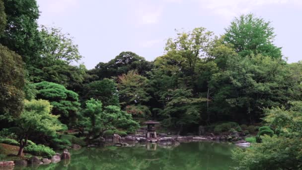 Pan wideo Tokio Metropolitan Park Kyufurukawa w japońskim ogrodzie Yukimi kamień latarnia z widokiem na staw Shinji w lecie. — Wideo stockowe