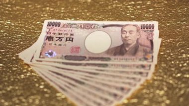 Yakın çekim odak videosu altın bir kağıt üzerinde 100.000 yen nakit.