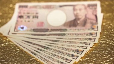 Yakın çekim odak videosu altın bir kağıt üzerinde 100.000 yen nakit.