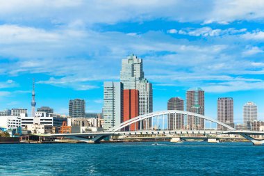 Tsukiji Ohashi 'nin Sumida nehri üzerindeki kemer köprüsü Kanni Caddesi' nin karşısında Tsukiji bölgesinin gökdelenleri ve arka planda Tokyo Skytree kulesi var..