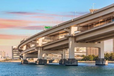 Tokyo Körfezi 'nde çifte katmanlı süspansiyon Gökkuşağı Köprüsü' ne karşı günbatımı gökyüzü üzerinde shuto ekspres yolu Daiba yolu ve aşağıdaki yurikamome monoray.