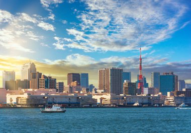 Japon römorkörleri Tokyo limanındaki Hinode rıhtımının önünde Shiba bölgesinin gökdelenleri ve Tokyo Kulesi ile birlikte gün batımında gökyüzünün altında seyrediyor..