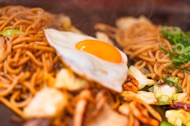 Yakisoba Japon eriştesinin üzerinde doğranmış soğanla kaplanmış sahanda yumurta.