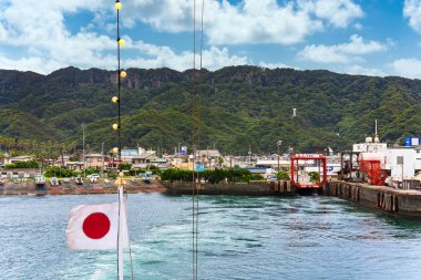 Chiba, Japonya - 18 Temmuz 2020: Kanaya balıkçı limanı Kanayamaru feribotundan Japon ulusal bayrağıyla Uraga Kanalı boyunca Nokogiri Dağı 'nın kayalıkları boyunca dalgalanan taş ocağı.