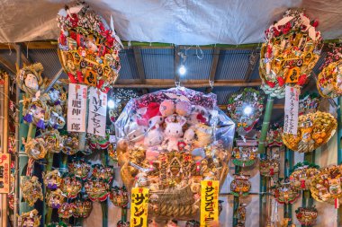 asakusa, japan - Kasım 08 2019: Ootori tapınağındaki Tori-no-Ichi Panayırı 'ndaki Hello Kitty gibi Sanrio karakterleriyle dekore edilmiş uğurlu tırmıklardan oluşan bir duvarın önünde yürüyen kalabalık.