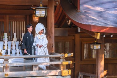 Tokyo, Japonya - 10 Ekim 2020: Geleneksel Japon shinto düğünü siyah haori kimonolu ve beyaz shiromuku 'lu bir çiftin Meiji Tapınağı' ndaki imparatorluk arması süslemesi altında..