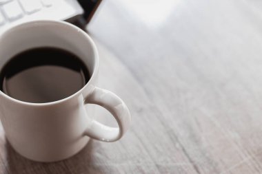 Siyah kahveyi beyaz fincanda, laptopu da ahşap masada kapat. Ev kavramından çalış