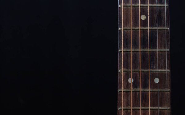 Close up old guitar neck on black background
