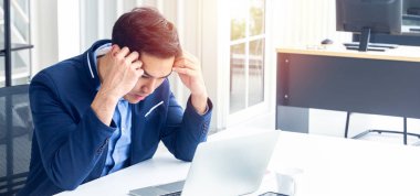 Modern bir ofiste oturan genç bir iş adamı. İş karlarının olumlu olmadığı konusunda kendini stresli hissediyor. Masasında bir bilgisayar tableti kağıt kalem grafiği ve kahve fincanı var..