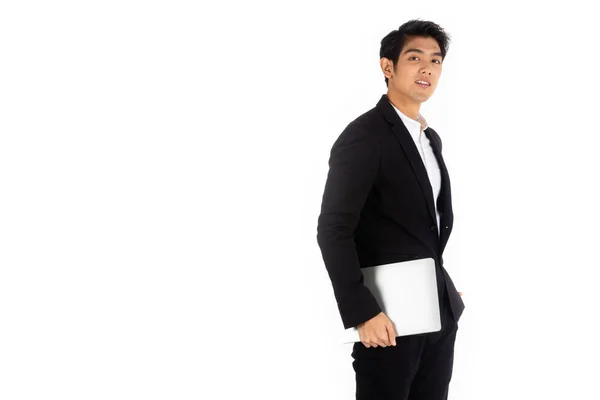 Yakışıklı genç işadamı Asya beyaz siyah saçlı siyah bir takım elbise giymek, bir gülümseme ve ayakta akıllı pozlar olmak. bir bilgisayar dizüstü bilgisayar tutun ve kullanabilirsiniz. Beyaz arka planda.