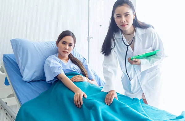 Asian young female patient lying on the bed improved symptoms allow the doctor to check and record the treatment results — Stock Photo, Image