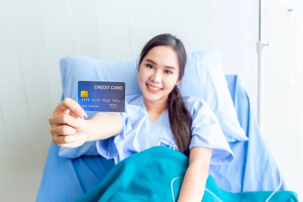 Asian young female patients show a demo credit card in hand. To pay medical expenses With smiles and bright facial expressions in the patient's ward. — Stock Photo, Image