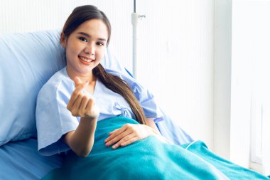 Asyalı genç kadın hastalar gülümsüyor ile bir mini kalp sembolü göstermek