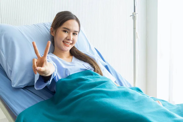 ベッドに横たわる青いシャツを着たアジアの若い女性患者 ストックフォト