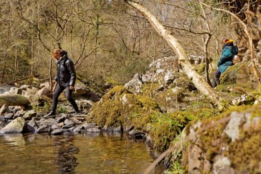 Snowdonia, Galler dağlarında bir dere üzerinde iki turist.