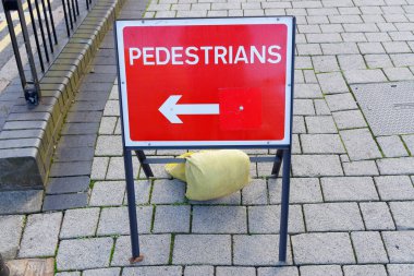 Kırmızı tabela yayaları sola yönlendiriyor..