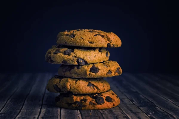 stack cookies with a chocolate crumb on a dark black and wood background