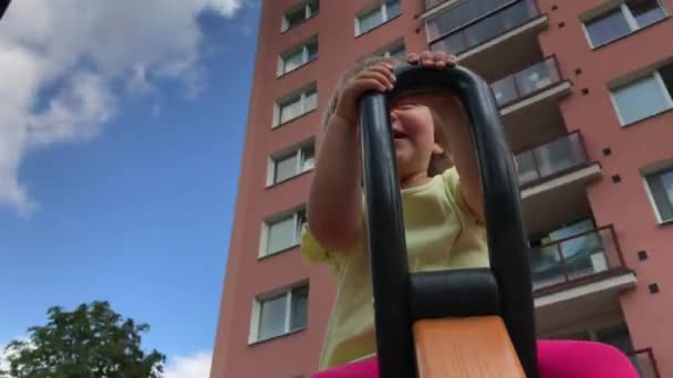 Lächelndes Kleinkind Auf Spinning Fahrt Auf Dem Städtischen Spielplatz Zwischen — Stockvideo