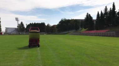 Kırmızı ve sarı çim kesme araç yeşil çim futbol sahası taşınıyor, çim-biçme maçtan önce yeşil sonra satırlarının keser