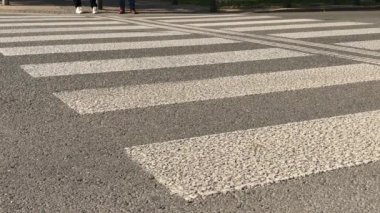 Birkaç yayalar küçük üzerinde zebra geçiş tarafından güneşli gün karşıdan karşıya. Yaya ayak şehirdeki sokak yaya geçidi tarafından yolun önlemek. İnsanlar bir yol boyunca yeşil ışık tarafından panda geçiş adım. Az insan yoldan git.
