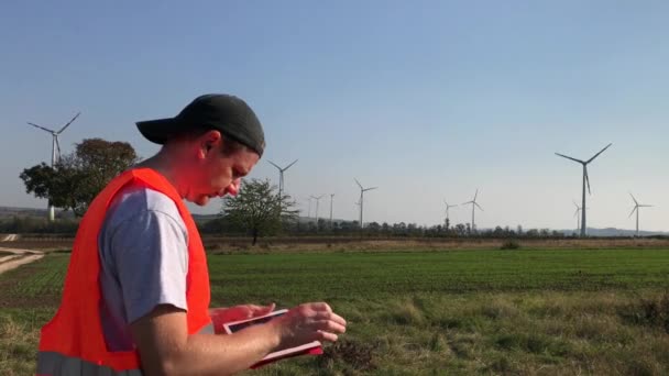Techniker Warnweste Blättert Windigen Sonnigen Tagen Der Nähe Funktionierender Windkraftanlagen — Stockvideo