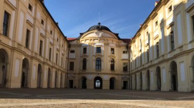 Önden görünüm Austerlitz kale güneşli sabah, South Moravia, Çek Cumhuriyeti. Slavkov u Brna palace, Barok güneş ışığında binanın iki kurşun. Güvercin flys çatı üzerinden. Gökyüzünde uçak sol buhar iz