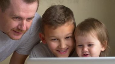 İki çocuk ve üst video izle, birlikte eğlenin. Baba, oğul ve kızı ekrana bak. Dostum, büyük kardeş ve küçük kardeş laptop öğrenin. Yetişkin ve kardeşleri, erkek ve kız görüntülemek için. Aile izle çizgi film çizgi film ya da çizgi film.