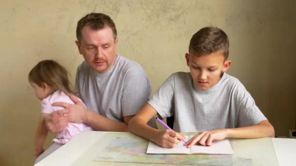 Permiso Paternidad Padre Ayudando Hijo Con Tarea Mientras Hija Trata — Vídeo de stock