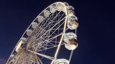 Dönme dolap tanınmaz insanlarla sokakta Noel fuarı Fuar alt sağ, koyu mavi gökten gelen aydınlatma akşam döner. Karnaval yeni yıl satış direksiyonda gözlem binmek. Eğlence binmek panoramik tekerlek dönme