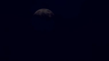 Siyah gece gökyüzüne bulutların arkasından çıkan ay. Dolunay yavaş yavaş gökyüzünde, doğal uydusu rüzgarlı akşam saatlerinde kurutma bulut yüzer. Ay karanlık bulutlar tarafından gizlenmiş. Bulutlu rüzgar esiyor