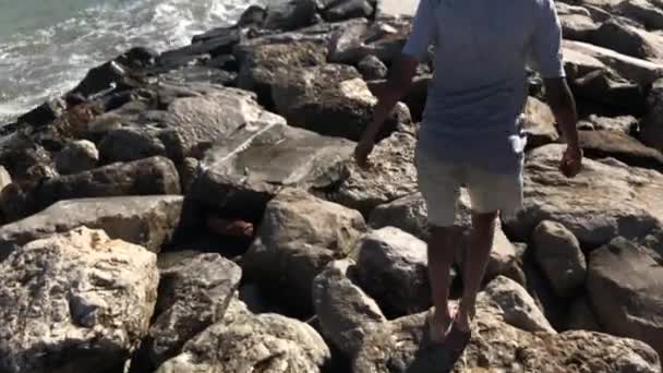 Niño Descalzo Saltando Corriendo Por Piedras Cerca Personas Irreconocibles Playa — Vídeos de Stock