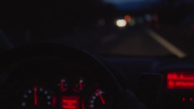 Direksiyon simidi gece yoldan sürüş sırasında araba içinde ellerinde kapatın. Taşıma sürücü karanlık karayolu üzerinde gelecek trafik aydınlatma. Tekerlek ve eller, bakıcısı görünümü içinde araba odaklanmaktadır. Açık pencere etkin yolu üzerinde odaklanmamış ulaşım