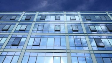 Mavi gökyüzü ve iş windows kurma yansıtan beyaz bulutlar. Modern mimari güzel hava. Camlar güneş ışığı üzerinde şehirde. Ofis Windows parlak gün. İnşaat dış ayna desen gökyüzü yansıması