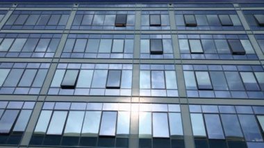 İş reflecteing mavi gökyüzü ve beyaz bulutlar Windows kurma. Modern mimari güzel hava. Camlar güneş ışığı üzerinde şehirde. Ofis Windows parlak gün. İnşaat dış ayna desen gökyüzü yansıması