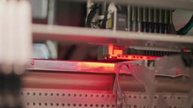 Kırmızı ışık, alt görünümü ile yüzey montaj makinesinde elektronik devre. Elektronik devreler üreten yüzey montaj teknolojisi. Bileşenleri yazdırılan öğeleri yüzeyine yerleştirilir. Bileşenleri toplama robot aygıt tarafından otomatik.