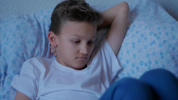 Στοχαστικό Έφηβο Αγόρι Ξαπλωμένο Στο Κρεβάτι Και Κρατώντας Δισκίο Αγγίζοντας — Αρχείο Βίντεο
