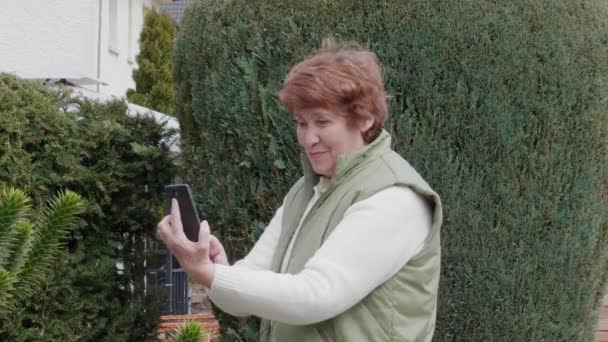Mujer Mayor Sonriente Recibiendo Selfie Por Teléfono Móvil Jardín Día — Vídeo de stock