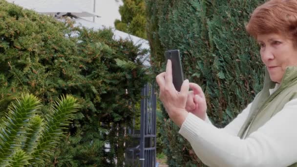 Gülümseyen Yaşlı Kadın Bahçede Fotoğraf Çekiyor Cep Telefonuyla Selfie Çekiyor — Stok video