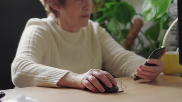 Mulher Sênior Clicando Mouse Mantendo Telefone Celular Mão Espaço Trabalho — Vídeo de Stock