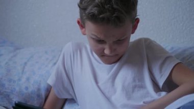 Genç çocuk evde tablet üzerinde sosyal ağ sohbet, gülümseyen, ekrandokunmadan, mesaj aylaklık, resim gönderme. Screenager yatak odasında pad medya içeriği izliyor. Yatakta internet tarama genç, mobil cihazda oyun oynamak