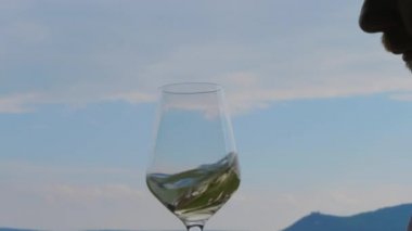 Adam mavi gökyüzüne karşı şarap kadehinde beyaz şarap kılık, koklama ve tatma dönen. Şarap kokusundan hoşlaå an, tatilde içen kişi. Restoranda bewhiskered şarap üreticisi elinde alkol ile Cam. Sommelier, şarap üreticisi şarap kalitesini inceleyerek