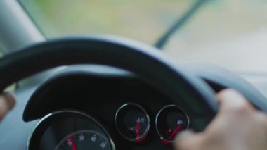Yağmurlu bir günde araba sürme, otomobil panosu yakın çekim, ön ekranda trafik toplantı bulanık anahatları. Yakıt tüketimi ile kontrol paneline, sürüş sırasında hız göstergesine odaklanın. El yapımı atış. Islı yolda ulaşım. Arabanın içinde bakıcı görünümü