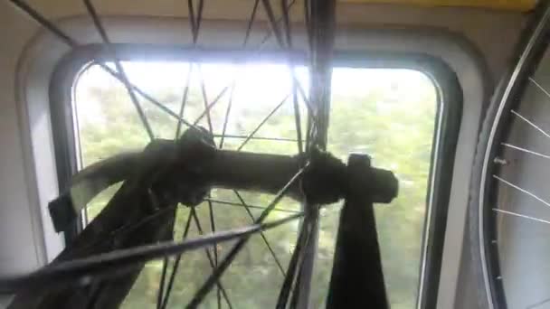 两辆自行车挂在架子上 在行驶的火车 城镇房屋 绿树和明亮的窗灯 手持拍摄 特写镜头 在火车站的货车内运输自行车 骑自行车旅行 户外活动 休闲运动理念 — 图库视频影像