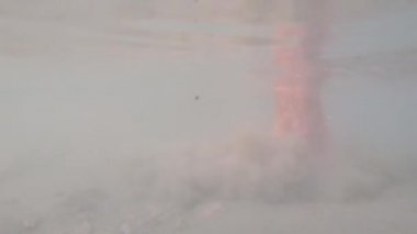 Çamurlu suda adımlar, hava kabarcıkları, kum karıştırma, el çekim. Ayaklar bulutlu suya basıyor, toprak su altında yüzen çamur bulutunu kısık, sığ bir şekilde yürüyor. Gölde çamurlu dipte yürüyün. Kıyıya yakın nehirdeki basamaklar