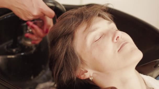 미용사는 이발소의 바에서 이발하기 머리를 이발사 유닛의 드레스용 머리를 씻습니다 — 비디오