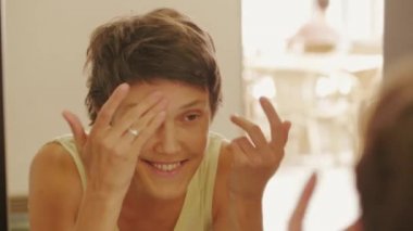 Berberdükkanında saç randevusundan sonra yüzünü temizleyen aynaya bakan kadın, gülümsüyor. Mutlu bayan kuaför güzellik salonu saç kesimi sonra dışarı sallayarak, sonra ayakta, arka hareket bulanık kuaför. Müşteri baş elbise sonra