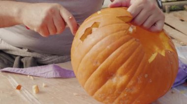 Cadılar bayramı balkabağı kabağı oyan erkek elleri. Cadılar bayramı balkabağı feneri için iki shot. Cadılar Bayramı partisi için dekorasyon hazırlayan kişi. Yetişkin balkabağını bıçakla kesiyor. Geleneksel sonbahar kutlaması için sembol hazırlığı